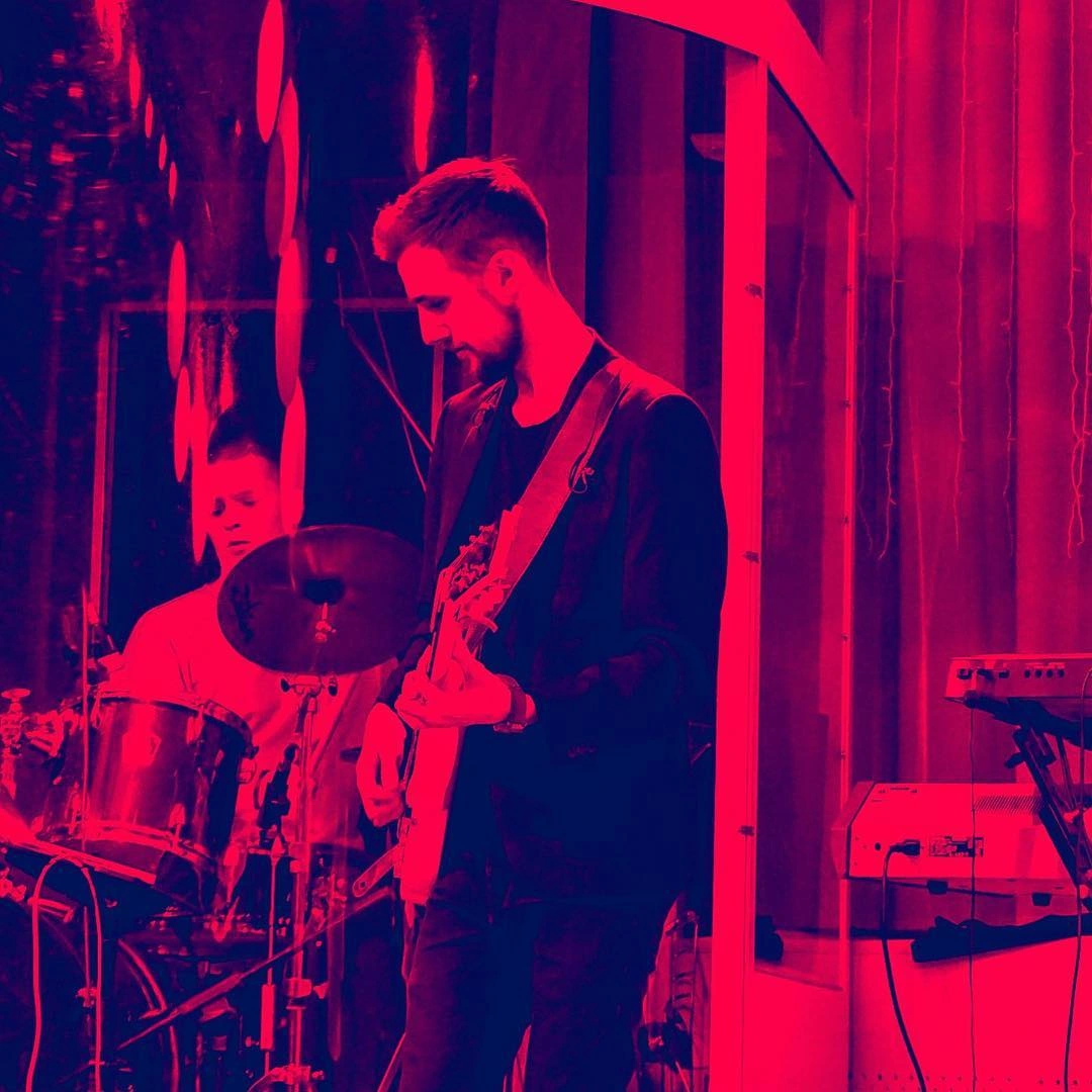 Roman playing guitar under red stage lights